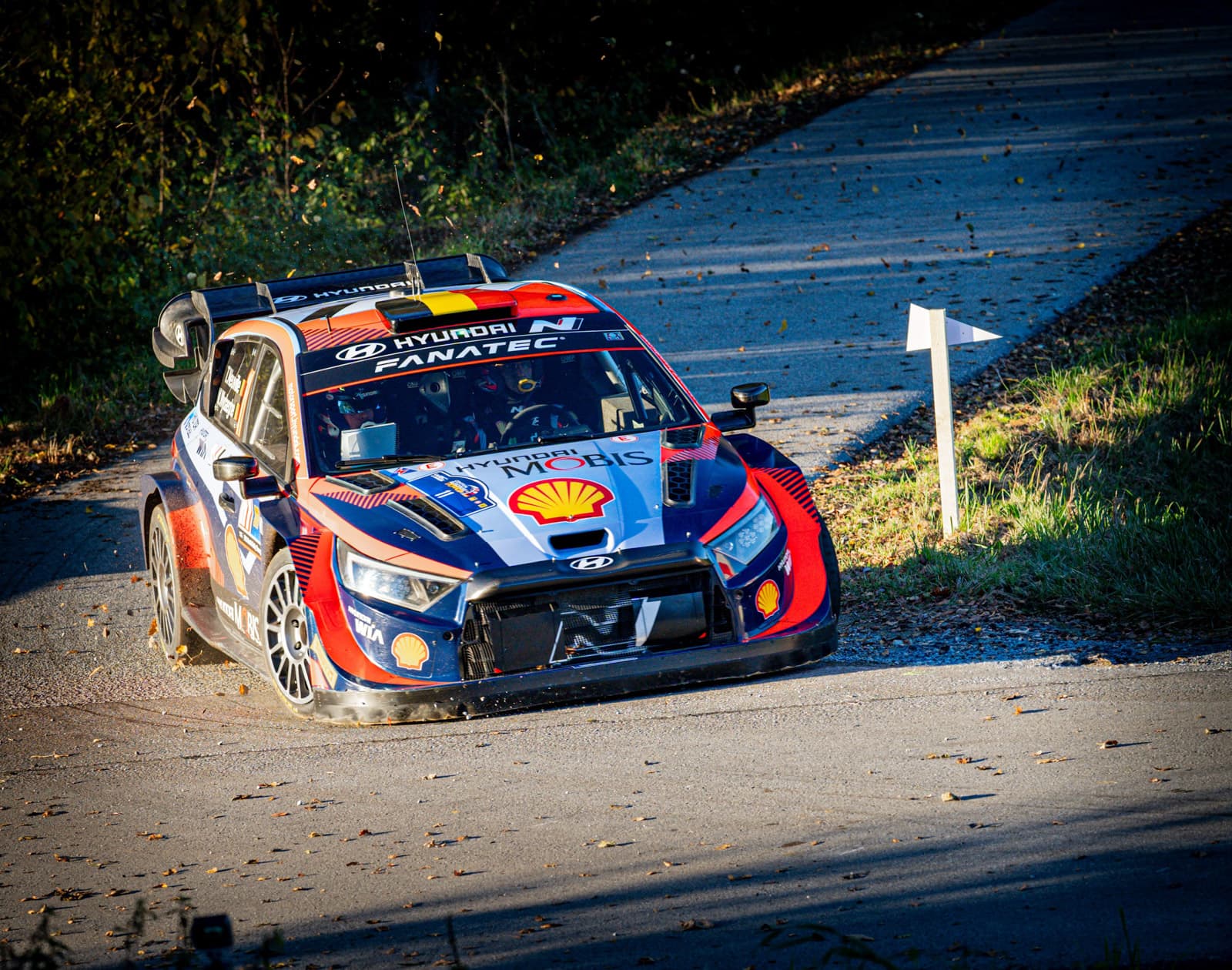 Hyundai i20 Rallye-Auto in rot-blauer WRC-Lackierung auf herbstlicher Waldstraße