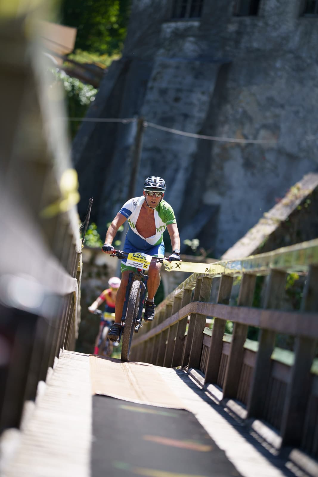 Mountainbiker fährt eine Holztreppen-Passage vor steiler Felswand hinunter