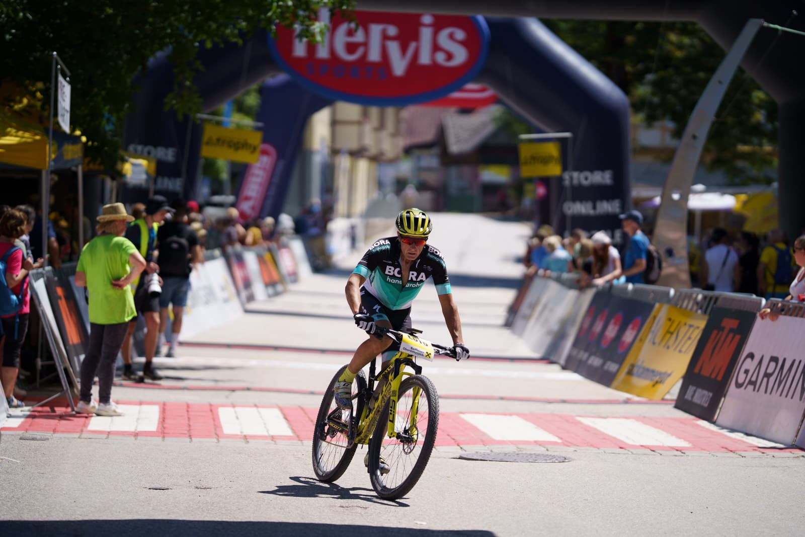Profi-Mountainbiker im Bora-hansgrohe-Trikot rollt nach dem Rennen über die Ziellinie