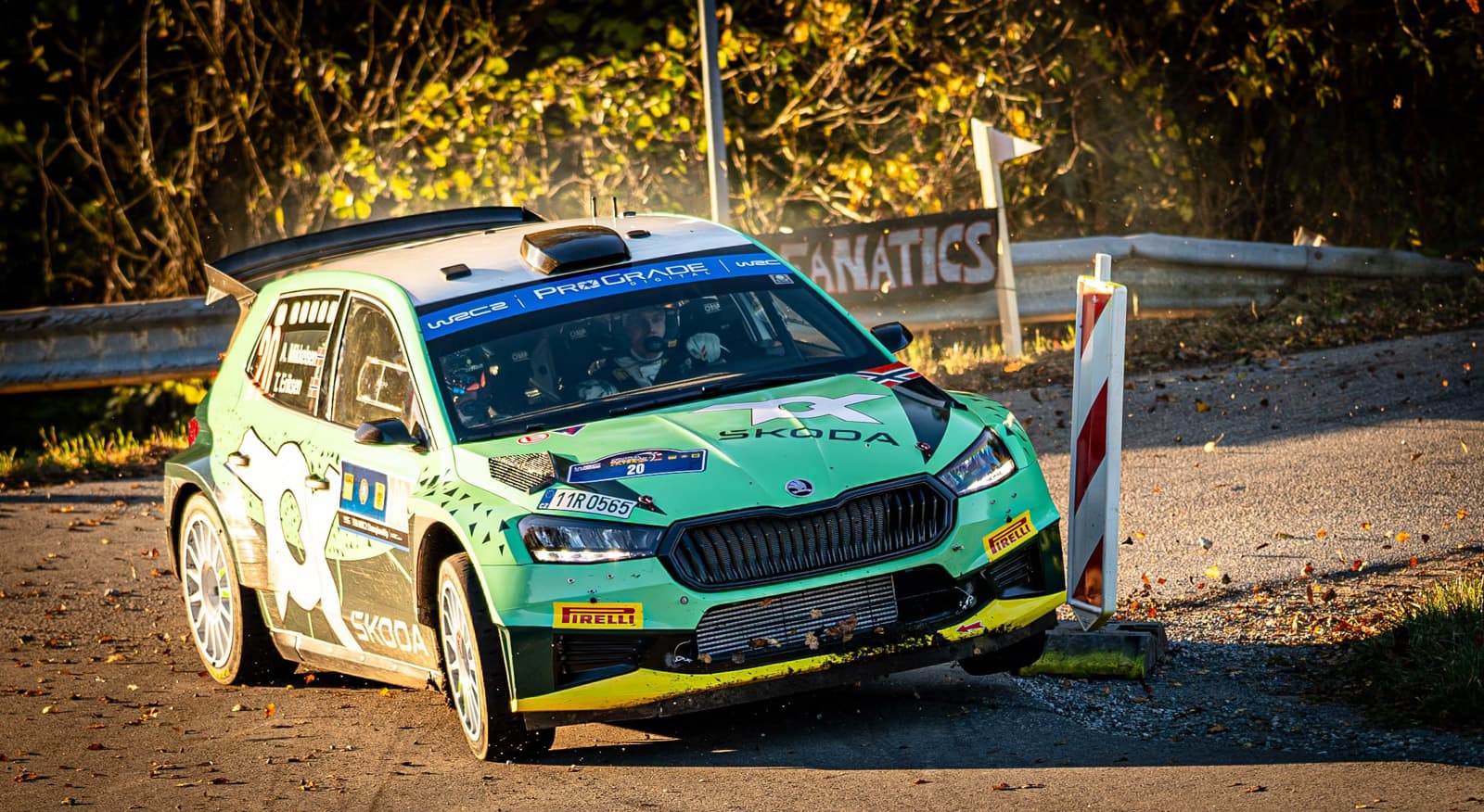 Grün-weiß lackierter Skoda Fabia Rallye-Wagen in schneller Kurvenfahrt