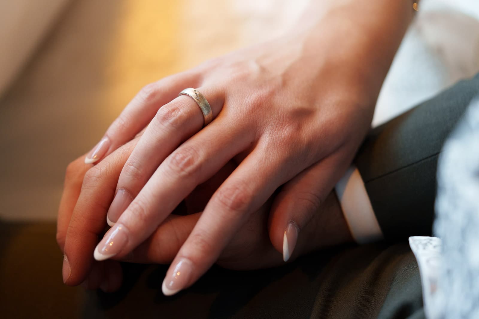Brautpaar-Hände übereinandergelegt, Ring mit drei Diamantsteinen am Damenfinger