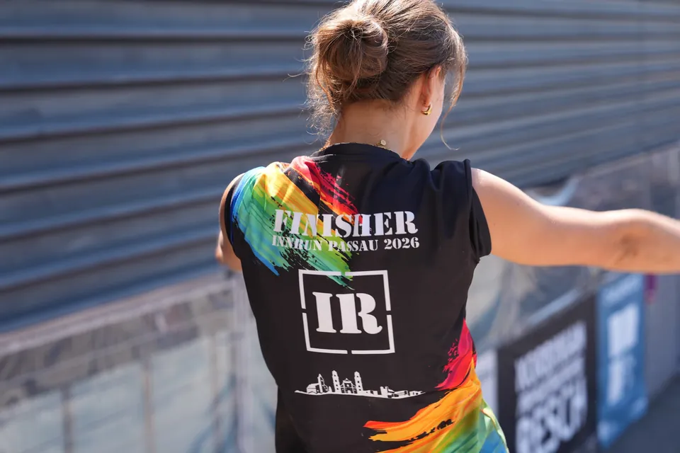 Teilnehmerin im Finisher-Shirt von hinten mit ausgestreckten Armen.