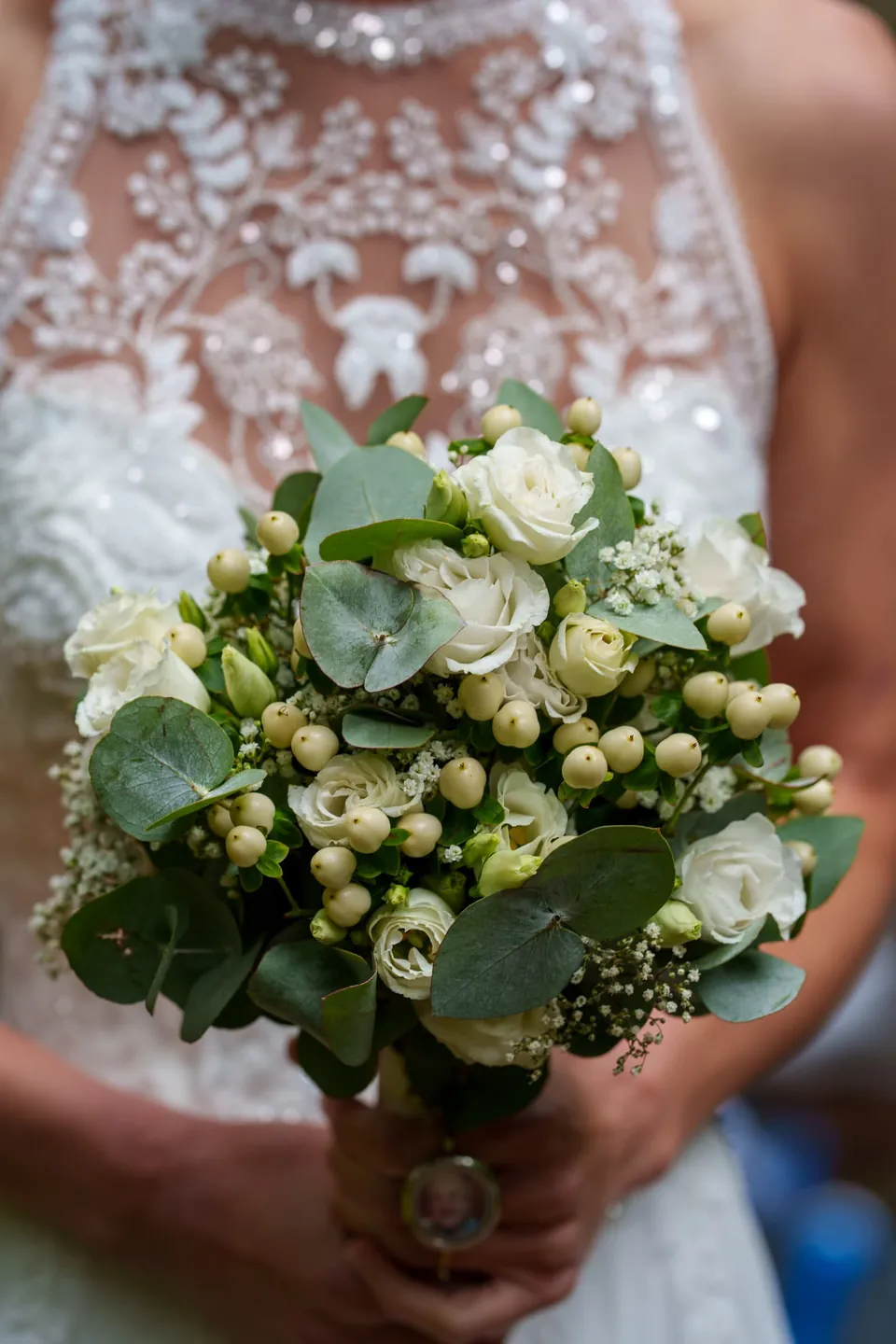 Braut hält einen Strauß aus weißen Blumen und grünen Blättern.
